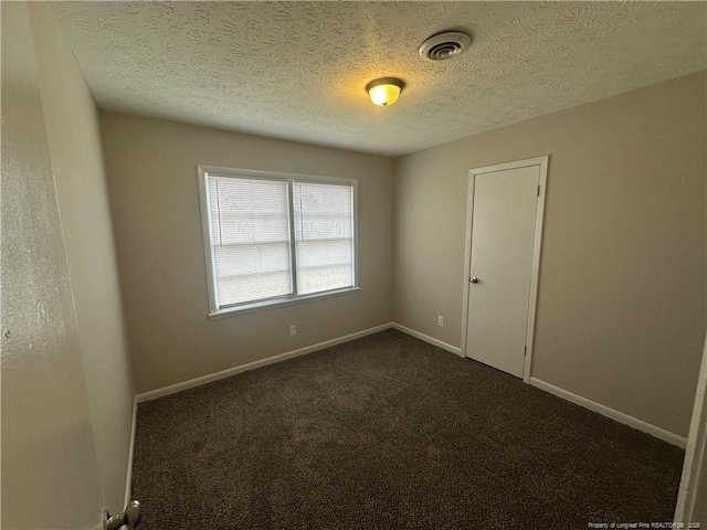 carpeted empty room featuring a textured ceiling