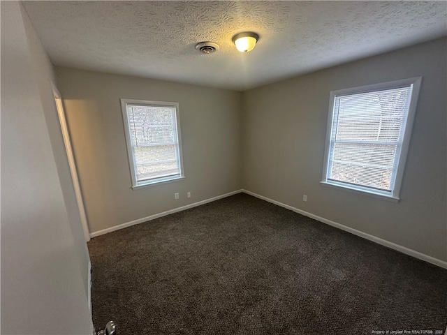 empty room featuring a textured ceiling and dark colored carpet