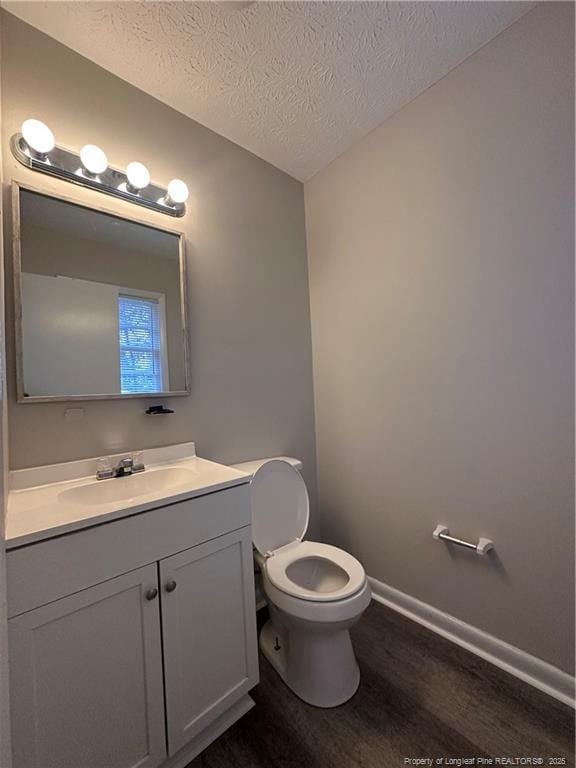 bathroom with toilet, vanity, a textured ceiling, and hardwood / wood-style floors