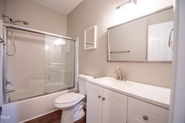 full bathroom featuring toilet, wood-type flooring, vanity, and bath / shower combo with glass door