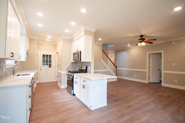 kitchen with appliances with stainless steel finishes, ornamental molding, sink, white cabinetry, and backsplash