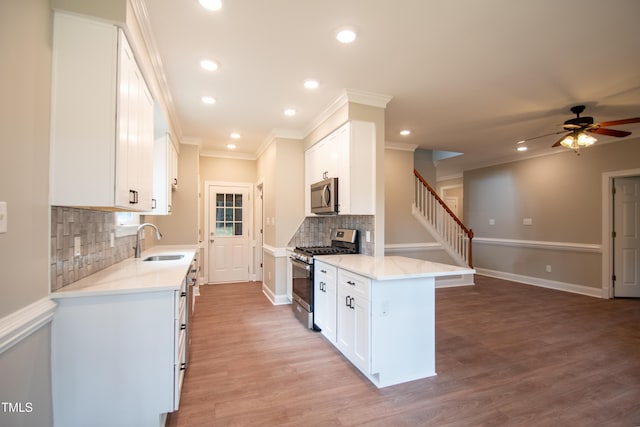 kitchen with stainless steel appliances, sink, white cabinets, ceiling fan, and decorative backsplash