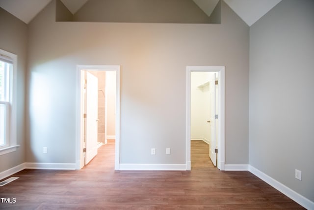 unfurnished bedroom with lofted ceiling, multiple windows, and a spacious closet