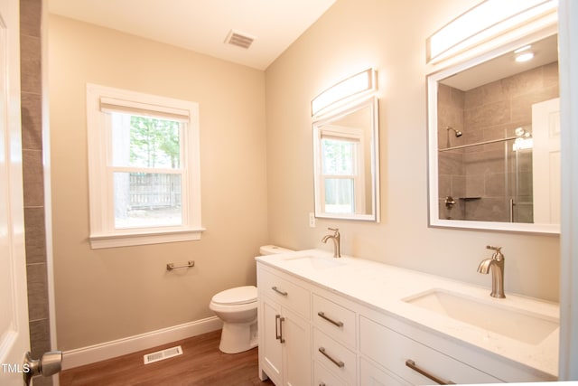 bathroom featuring toilet, vanity, hardwood / wood-style floors, and tiled shower