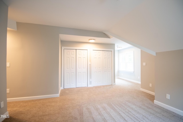 additional living space featuring lofted ceiling and light carpet