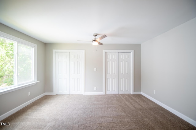 unfurnished bedroom with multiple closets, ceiling fan, and carpet