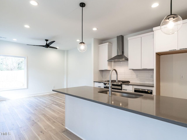 kitchen with decorative light fixtures, white cabinetry, ceiling fan, light hardwood / wood-style floors, and wall chimney range hood