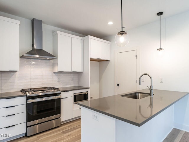 kitchen with sink, white cabinetry, wall chimney range hood, pendant lighting, and appliances with stainless steel finishes