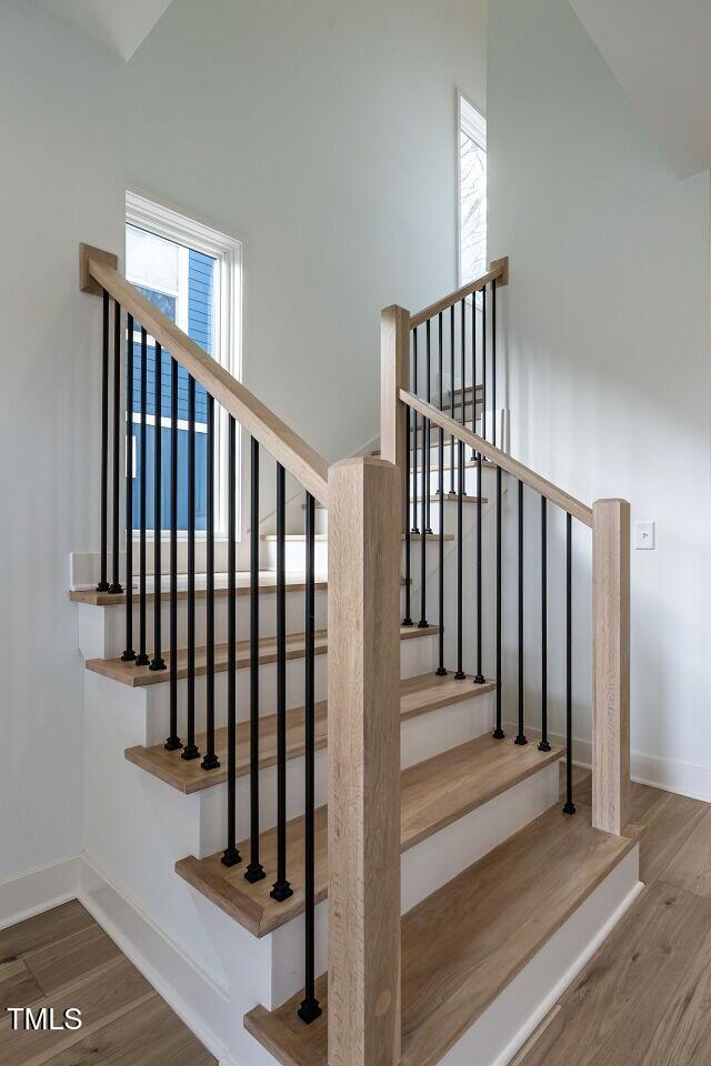 stairs with hardwood / wood-style floors and a healthy amount of sunlight