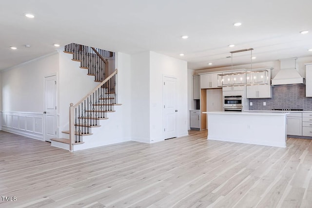 kitchen featuring premium range hood, light hardwood / wood-style flooring, pendant lighting, and a center island