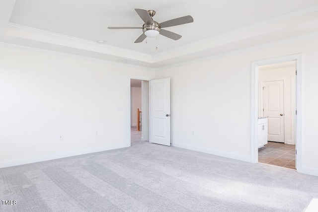 carpeted spare room with a raised ceiling, ceiling fan, and crown molding