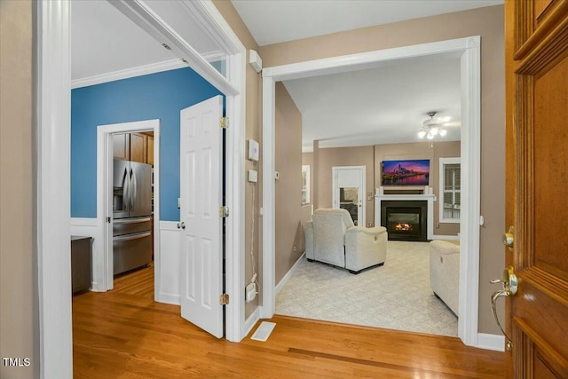 corridor with light wood-type flooring and ornamental molding