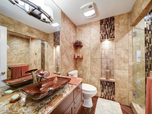 bathroom featuring toilet, vanity, tile walls, hardwood / wood-style flooring, and an enclosed shower