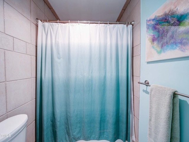 bathroom featuring toilet, tile walls, and a shower with shower curtain