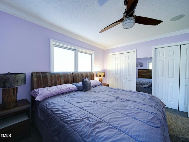 carpeted bedroom featuring ceiling fan, multiple closets, ornamental molding, and a textured ceiling