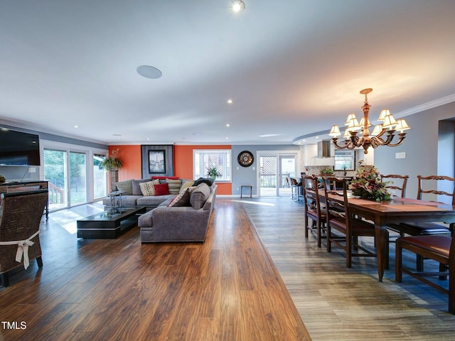 living room featuring wood-type flooring, an inviting chandelier, and ornamental molding