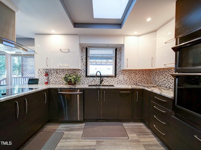 kitchen with stainless steel dishwasher, island range hood, black electric stovetop, and white cabinetry