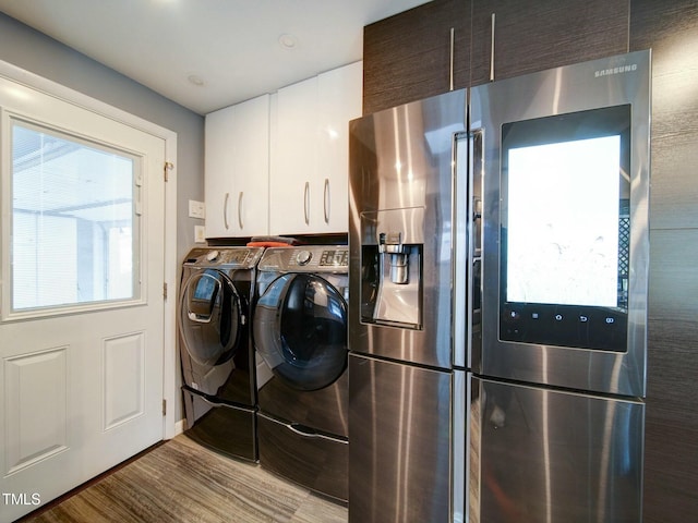 laundry room with light hardwood / wood-style floors, cabinets, and washing machine and clothes dryer