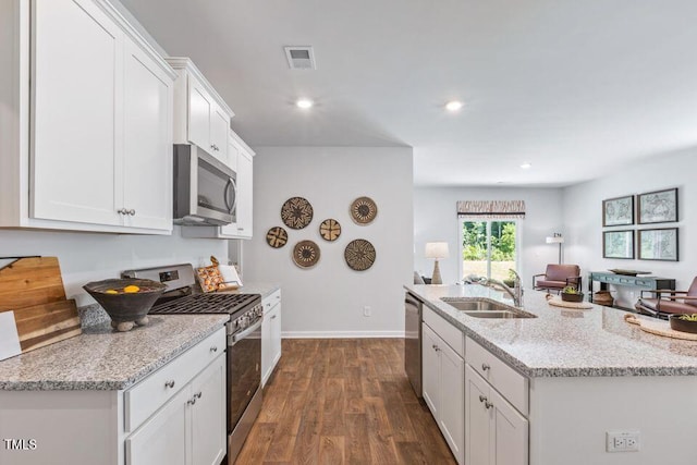 kitchen with stainless steel appliances, sink, white cabinets, light stone counters, and dark hardwood / wood-style flooring