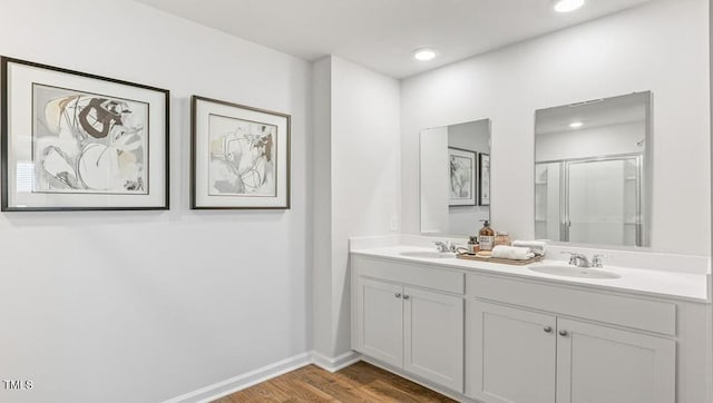 bathroom with wood-type flooring, vanity, and a shower with shower door