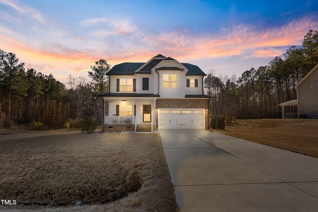 view of front of property with covered porch, a lawn, and a garage