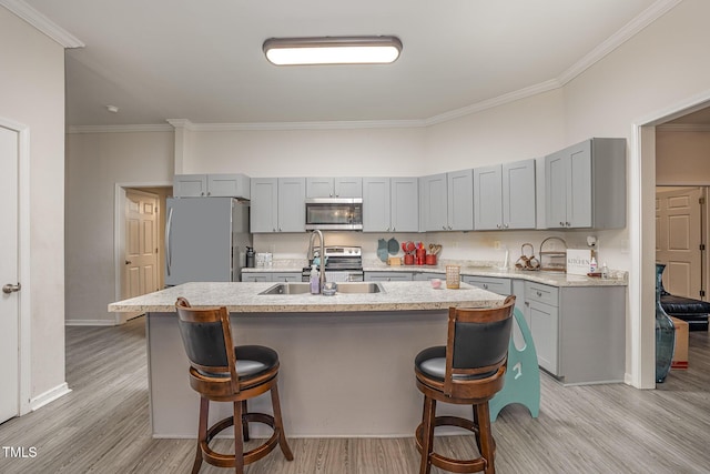 kitchen with a kitchen breakfast bar, a kitchen island with sink, appliances with stainless steel finishes, crown molding, and sink