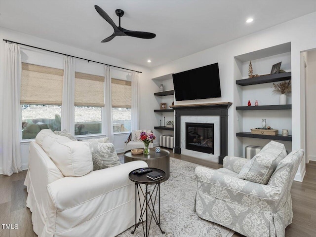 living room featuring ceiling fan, a wealth of natural light, hardwood / wood-style flooring, and built in features