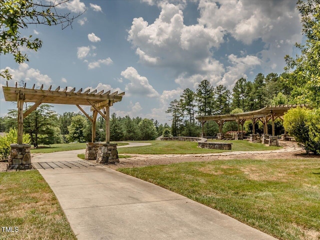 view of property's community featuring a lawn and a pergola