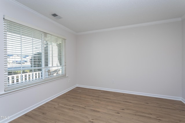 empty room featuring a textured ceiling, ornamental molding, and wood-type flooring