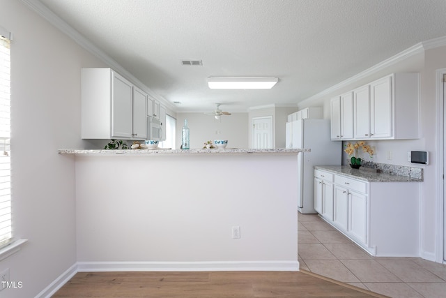 kitchen featuring kitchen peninsula, white appliances, white cabinetry, ornamental molding, and light stone counters