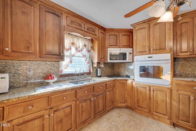 kitchen featuring sink, white appliances, backsplash, and light stone counters