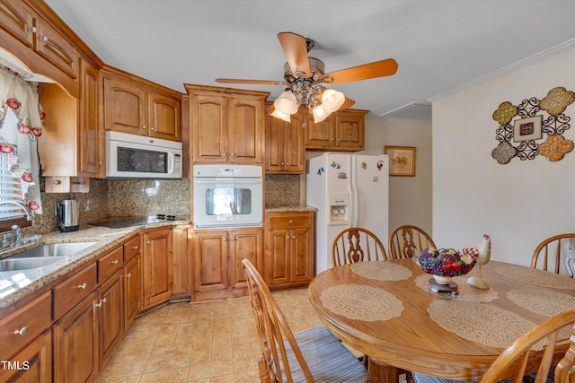 kitchen with white appliances, tasteful backsplash, light stone countertops, and sink