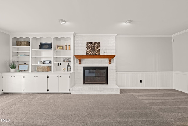 unfurnished living room featuring crown molding, a brick fireplace, light colored carpet, and built in shelves