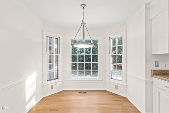 unfurnished dining area featuring ornamental molding, a healthy amount of sunlight, and light hardwood / wood-style flooring