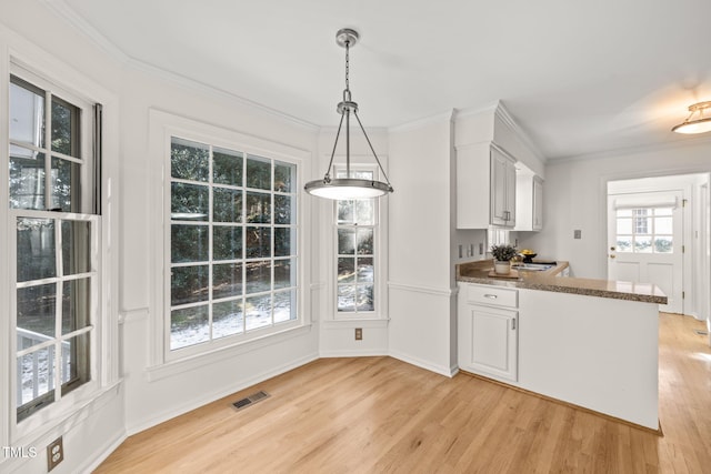 kitchen featuring white cabinetry, ornamental molding, pendant lighting, and light wood-type flooring