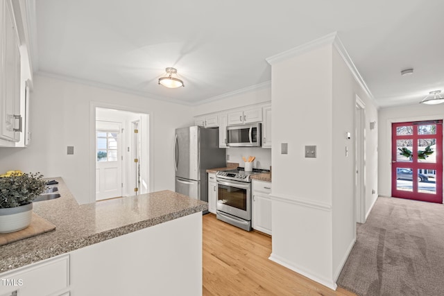 kitchen featuring crown molding, stainless steel appliances, white cabinets, light colored carpet, and kitchen peninsula