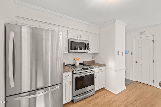 kitchen with stone counters, appliances with stainless steel finishes, white cabinets, ornamental molding, and light wood-type flooring