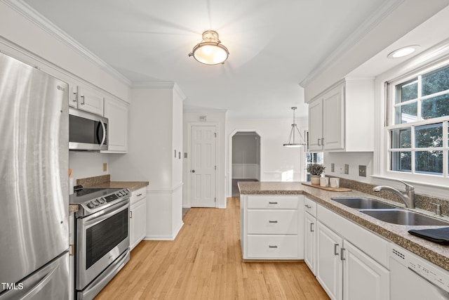 kitchen with appliances with stainless steel finishes, decorative light fixtures, sink, white cabinets, and kitchen peninsula