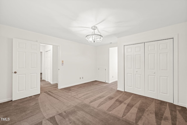 unfurnished bedroom featuring a notable chandelier, dark carpet, and a closet