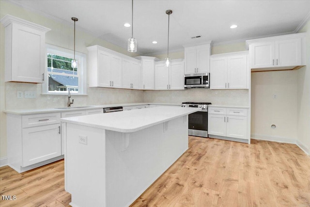 kitchen featuring sink, stainless steel appliances, white cabinets, and a center island