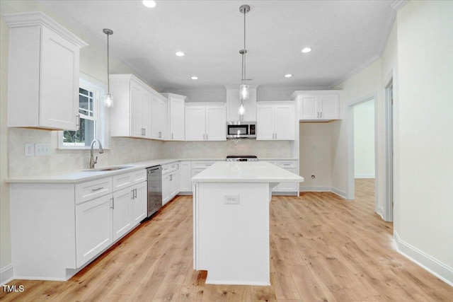 kitchen featuring stainless steel appliances, sink, white cabinetry, a kitchen island, and pendant lighting