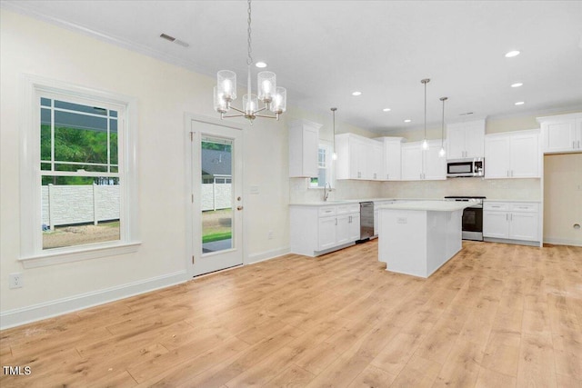 kitchen featuring white cabinets, stainless steel appliances, decorative light fixtures, and a kitchen island