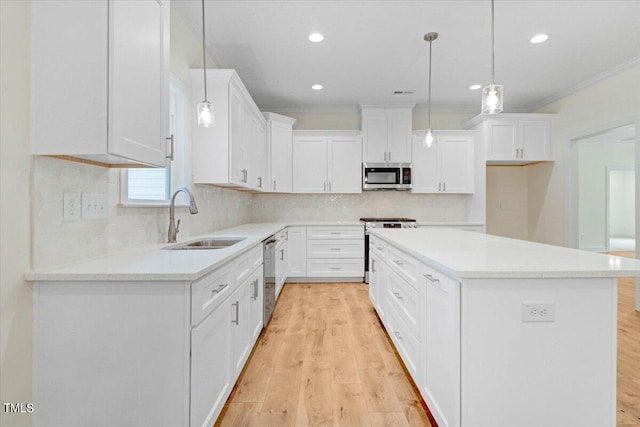 kitchen featuring a center island, hanging light fixtures, stainless steel appliances, white cabinetry, and sink