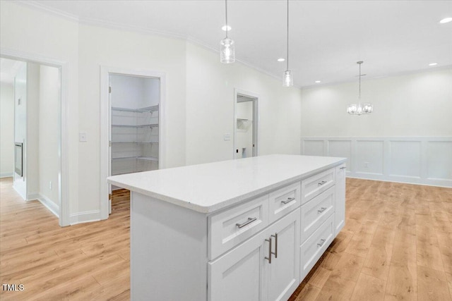 kitchen with white cabinets, ornamental molding, pendant lighting, and a center island