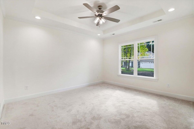 carpeted spare room featuring a raised ceiling and ceiling fan