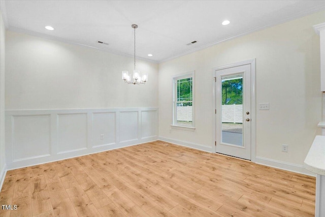 unfurnished dining area with crown molding, a chandelier, and light hardwood / wood-style flooring