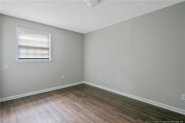 spare room with a textured ceiling and dark hardwood / wood-style flooring