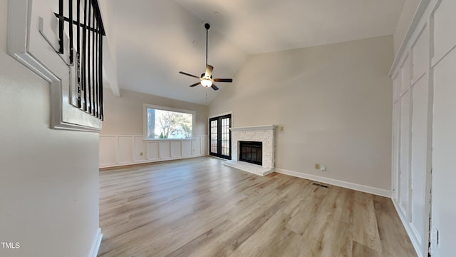 unfurnished living room with vaulted ceiling, a brick fireplace, ceiling fan, and light hardwood / wood-style floors