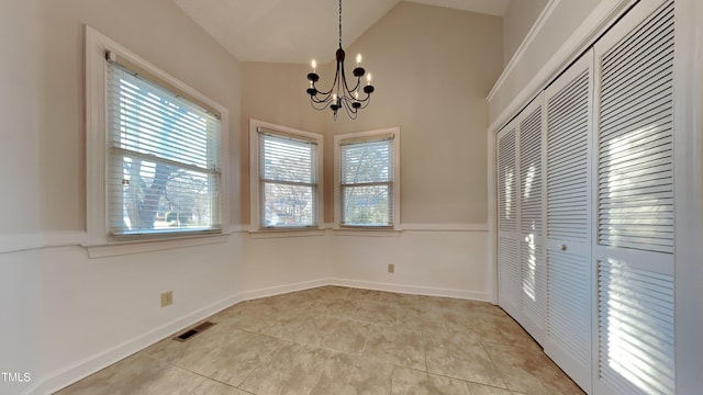 unfurnished dining area with a notable chandelier, vaulted ceiling, and light tile patterned floors