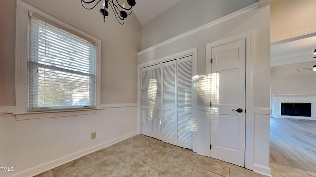 interior space featuring lofted ceiling, light tile patterned flooring, and ceiling fan with notable chandelier